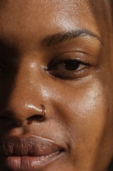 A detailed close-up of a woman's face highlighting her skin texture and nose ring.