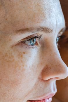 Side view of crop female with freckles on natural skin looking away with gentle smile